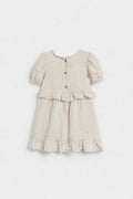 Back view of girls’ beige linen dress with wooden button closure and ruffle details