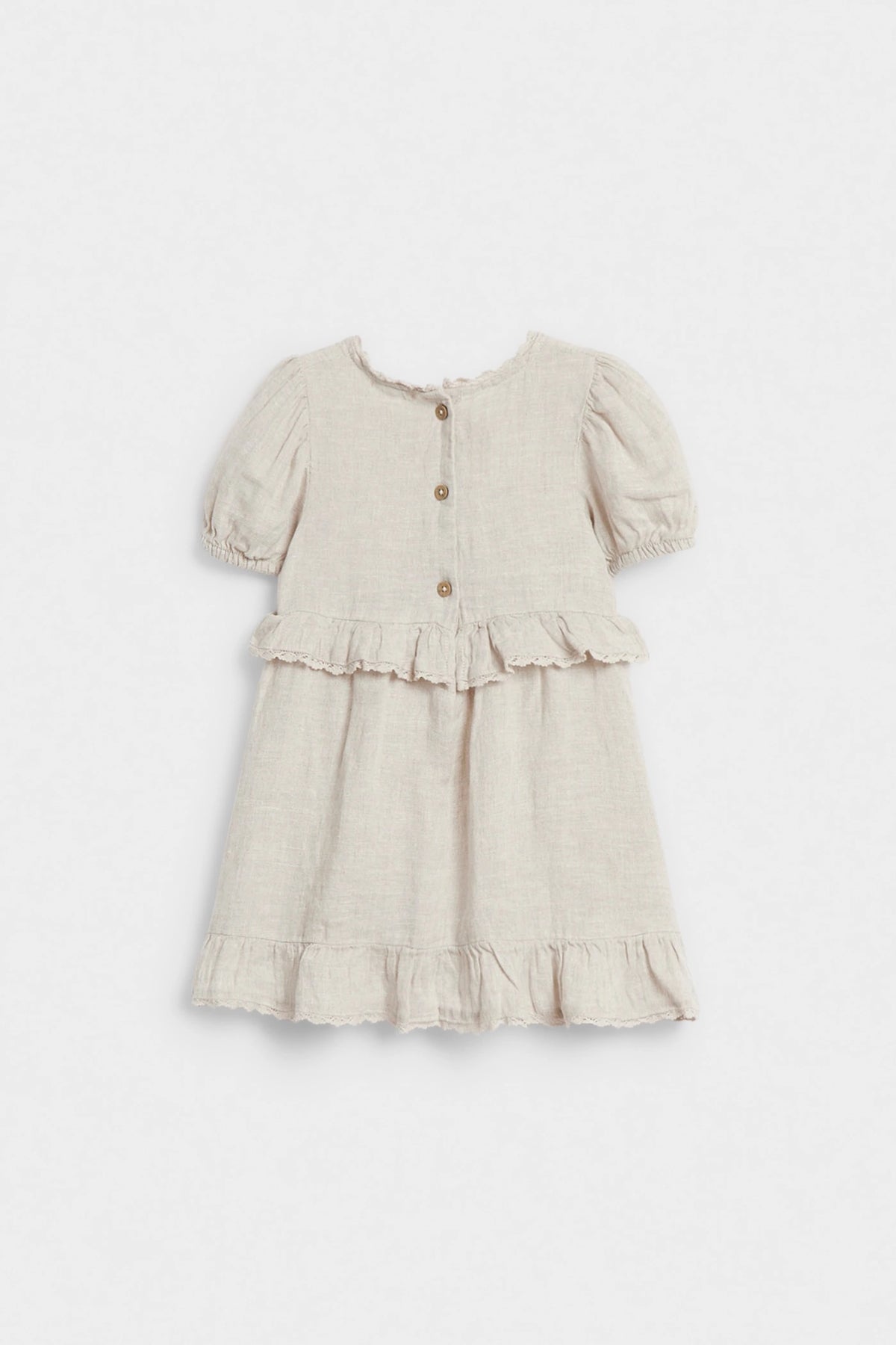 Back view of girls’ beige linen dress with wooden button closure and ruffle details
