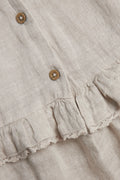 Close-up of girls’ beige linen dress fabric with wooden buttons and lace-trimmed ruffle detail