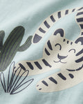 Close-up of striped big cat and cactus graphic print on mint blue boys' cotton t-shirt, showing cream and navy illustrated design detail