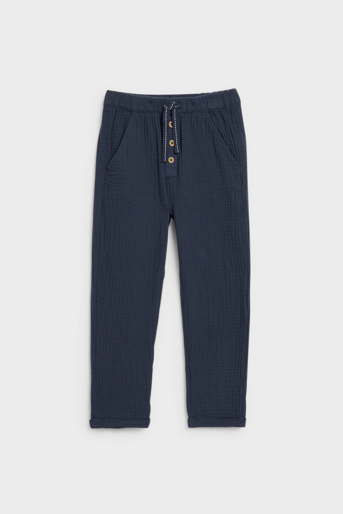 Navy blue kids' muslin trousers with drawstring waist, button placket and side pockets, flat lay — PTex Fashion