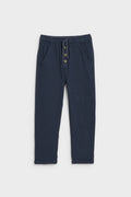 Navy blue kids' muslin trousers with drawstring waist, button placket and side pockets, flat lay — PTex Fashion