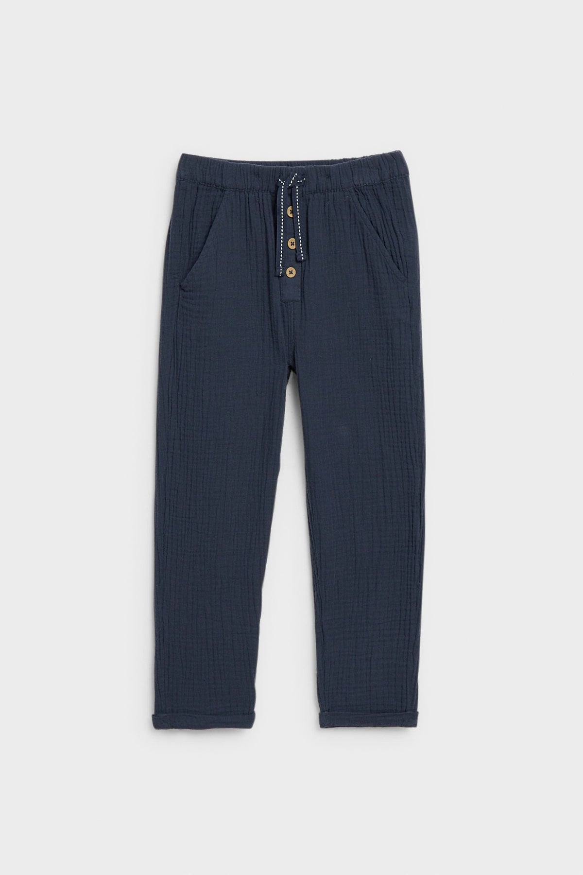 Navy blue kids' muslin trousers with drawstring waist, button placket and side pockets, flat lay — PTex Fashion