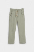 Sage green kids' muslin trousers with elasticated waist, button placket and side pockets, flat lay — PTex Fashion