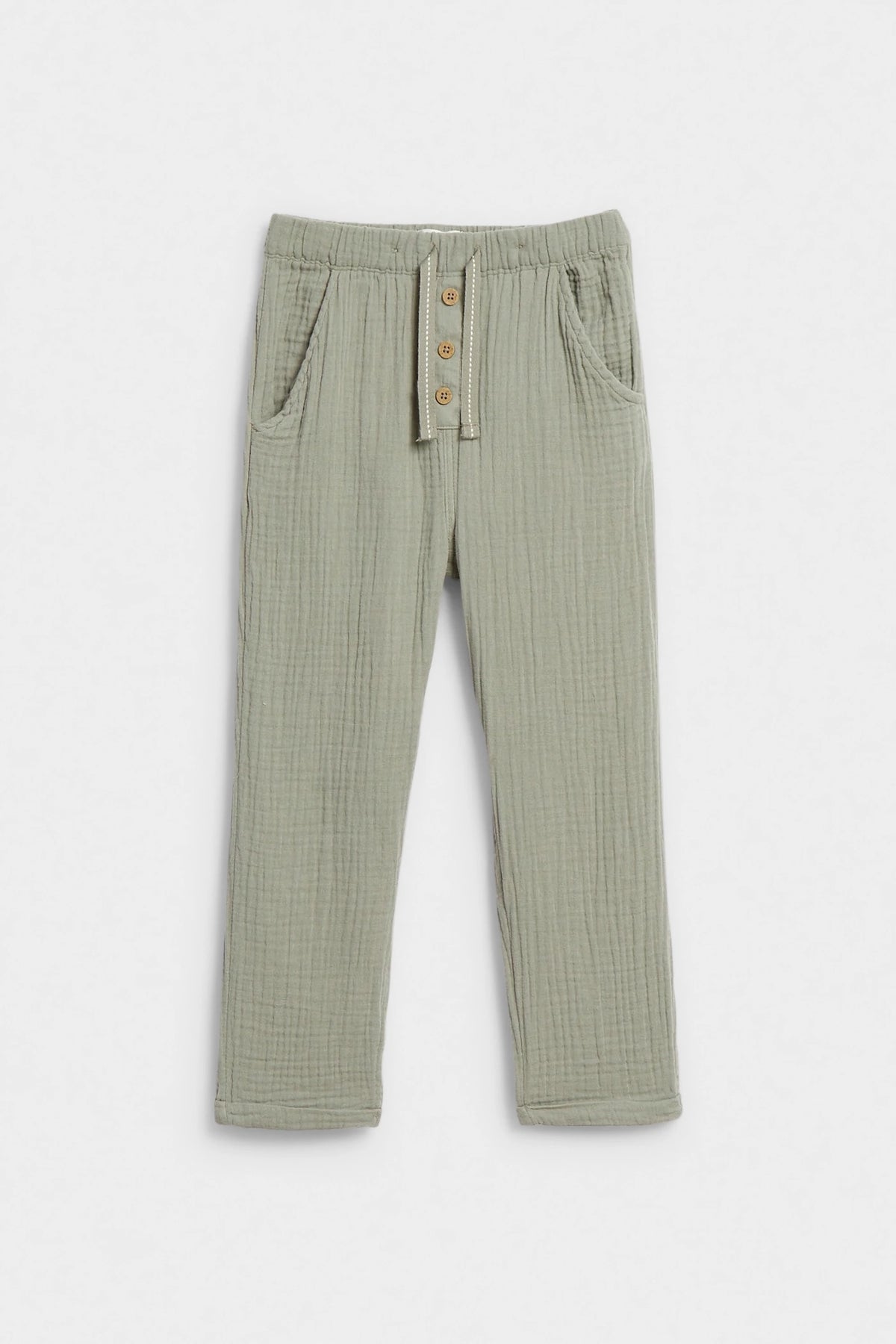 Sage green kids' muslin trousers with elasticated waist, button placket and side pockets, flat lay — PTex Fashion