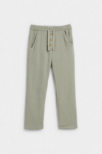 Sage green kids' muslin trousers with elasticated waist, button placket and side pockets, flat lay — PTex Fashion