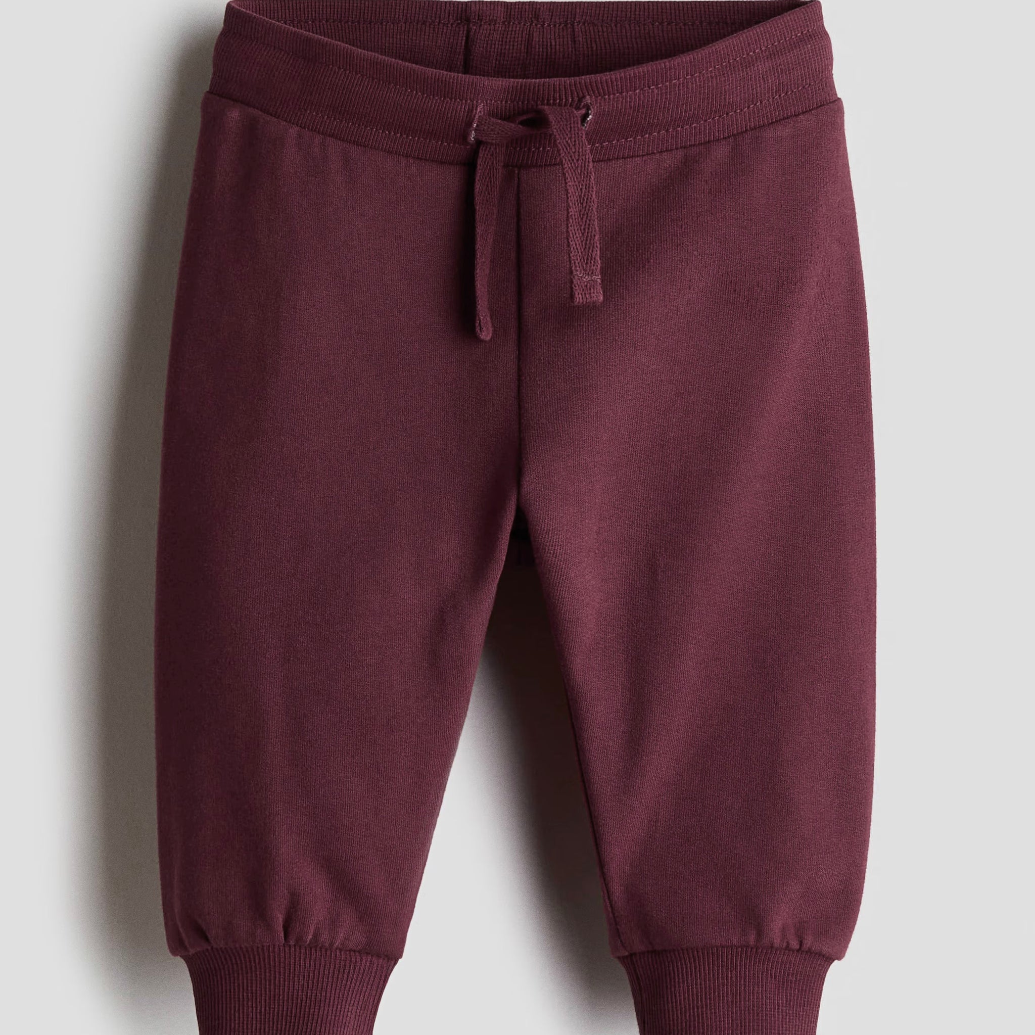 Maroon sweatpants on a light gray background