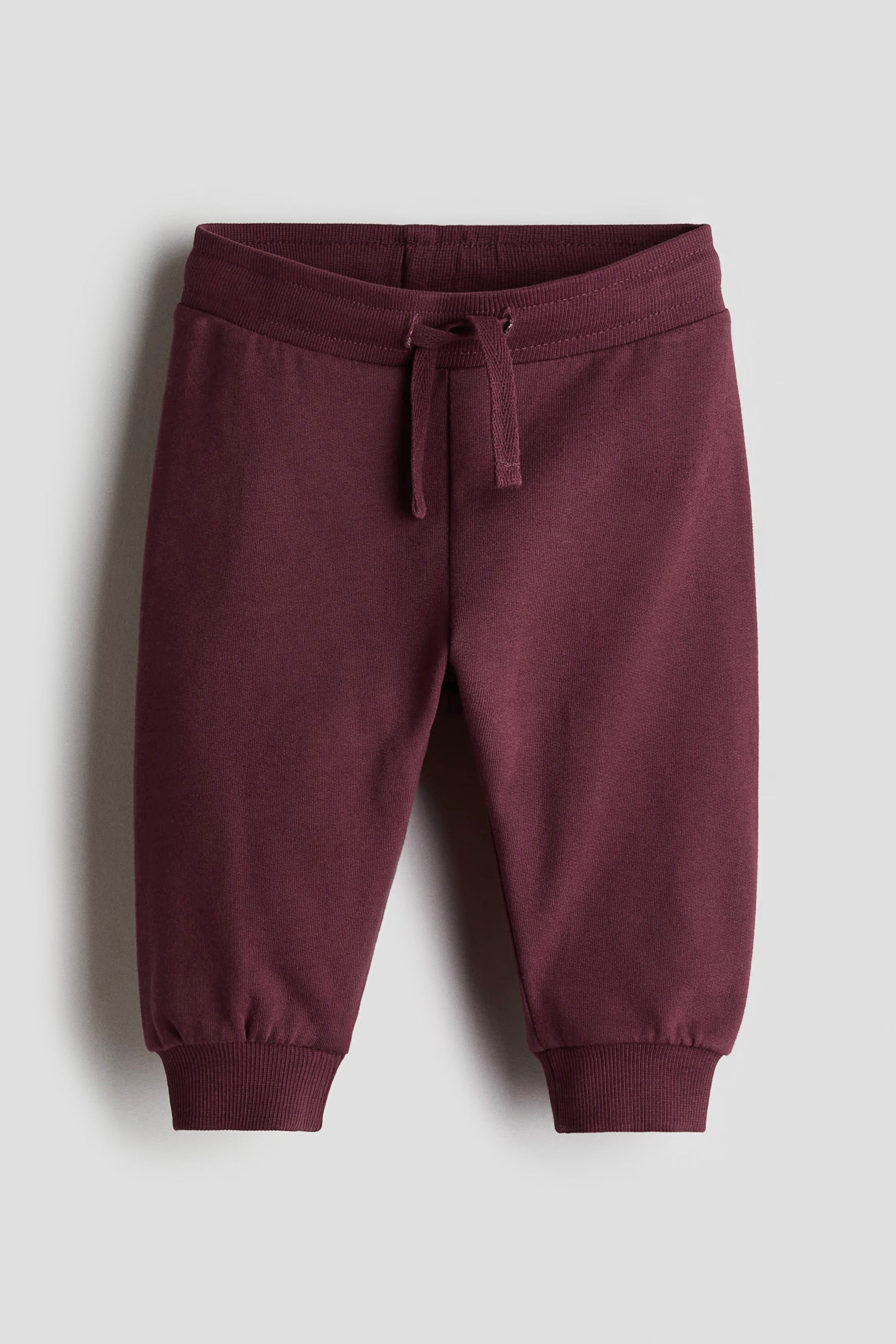 Maroon sweatpants on a light gray background