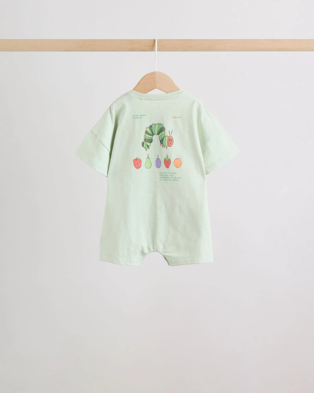 Mint green baby romper front view with caterpillar graphic and wooden button placket on wooden hanger