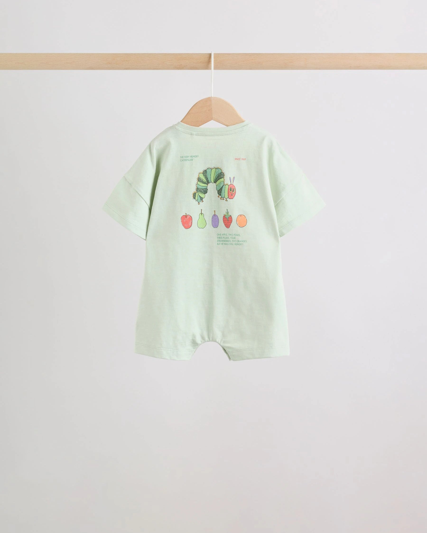 Back view of mint green baby romper showing full caterpillar and fruit print with storybook text