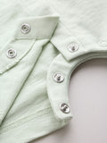 Close-up of silver press-stud snap fasteners at crotch of mint green baby romper