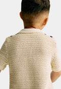 Person wearing a beige knitted polo against a white background