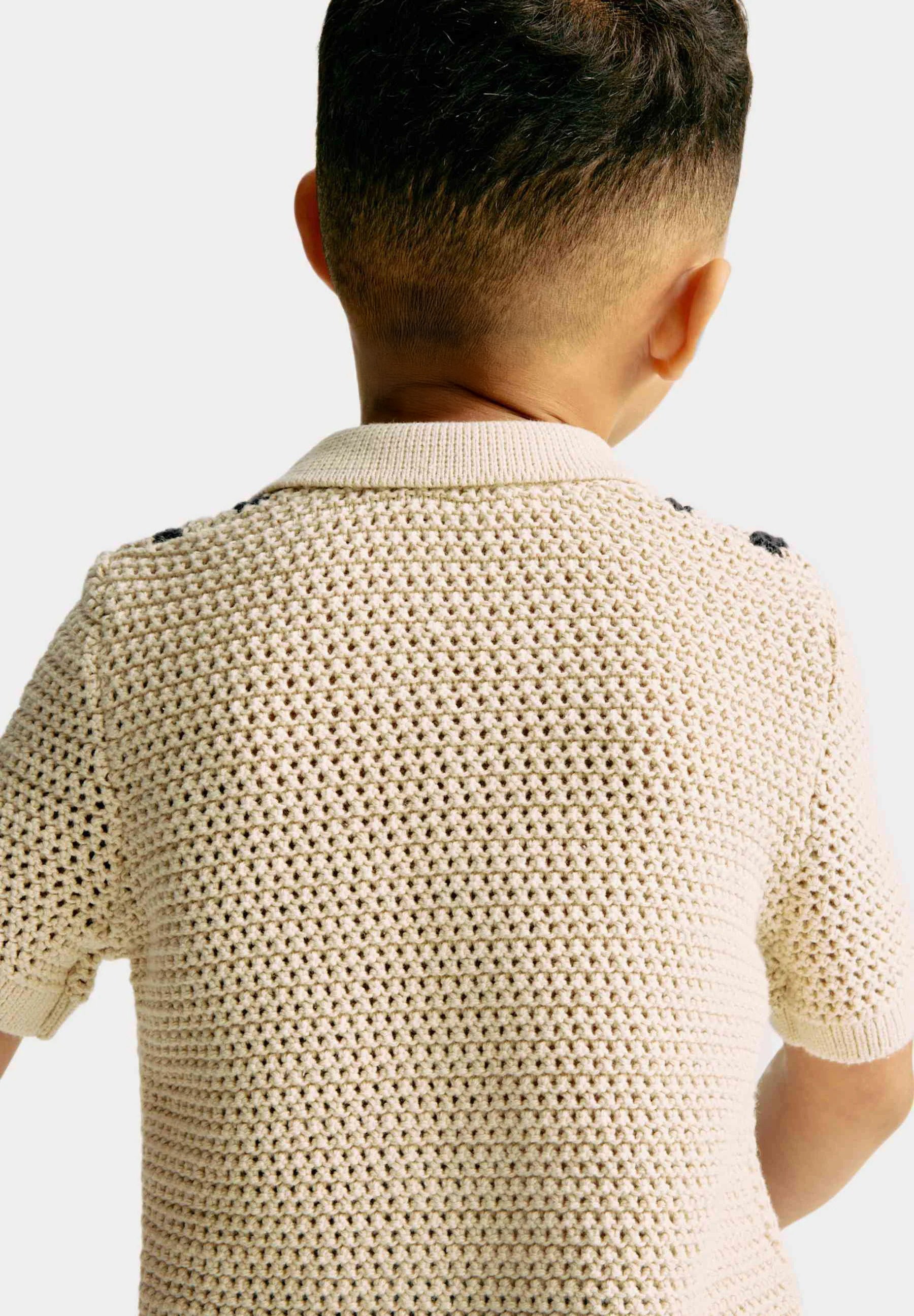 Person wearing a beige knitted polo against a white background
