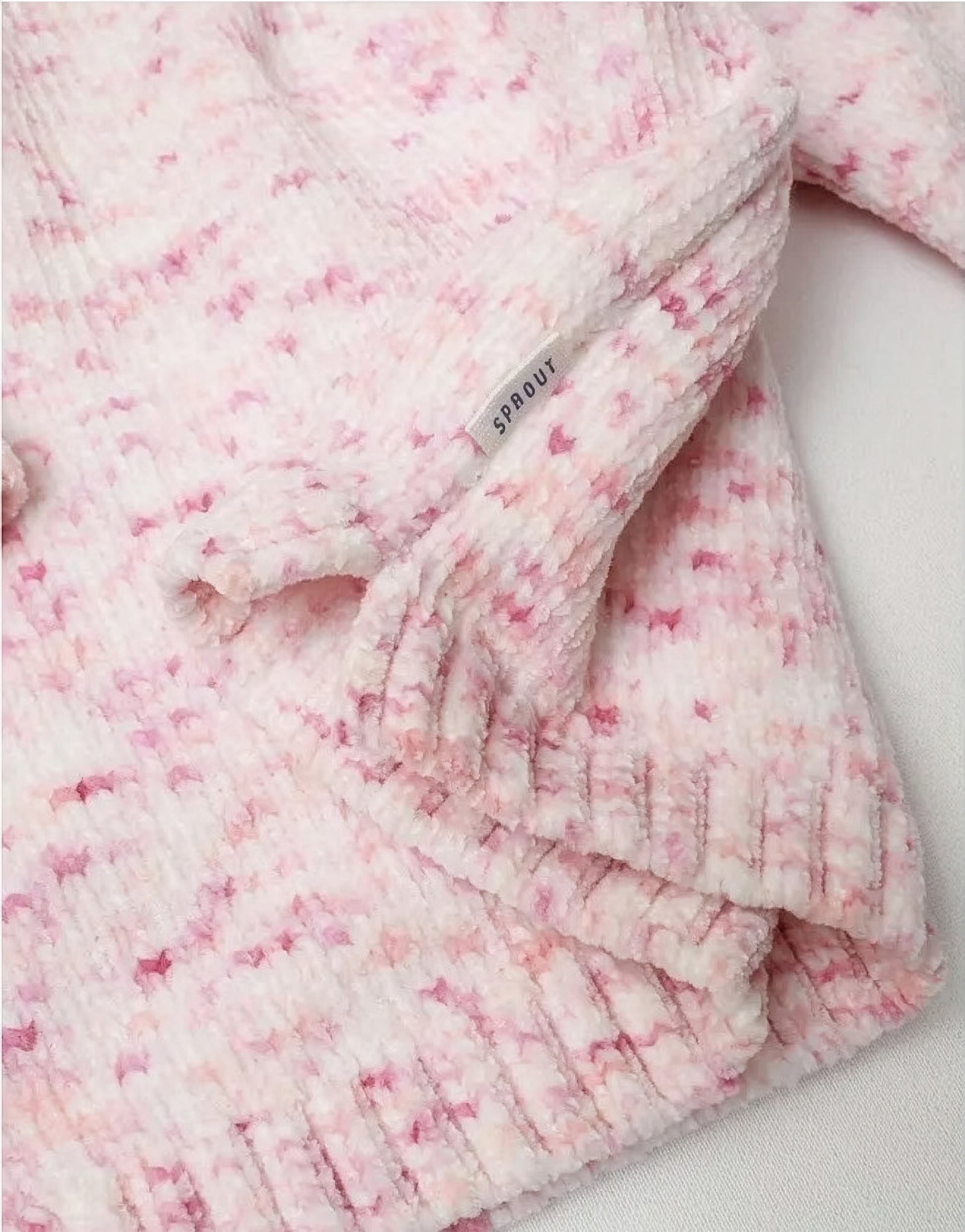 Pink and white textured baby jumper on a light background