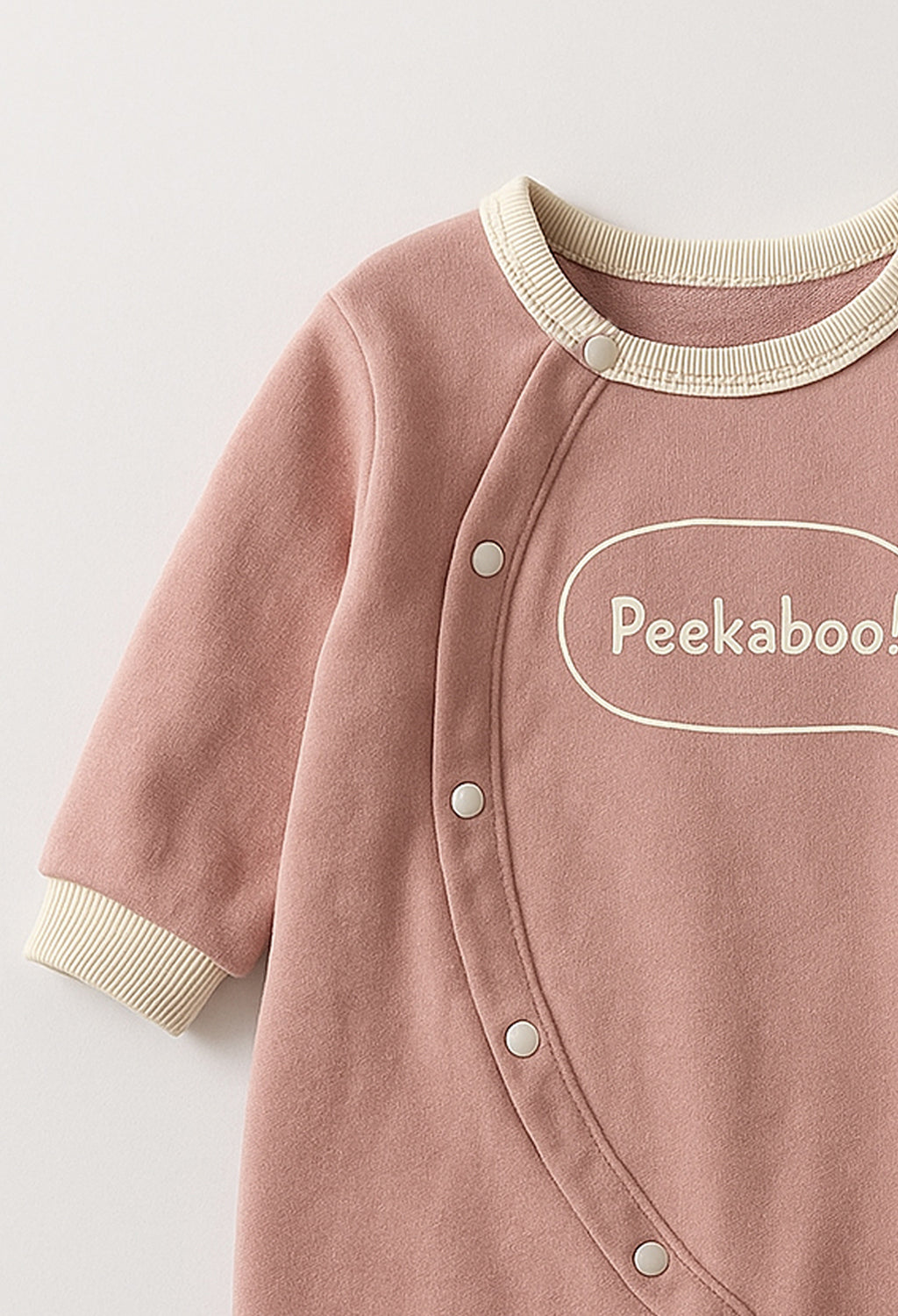 Pink baby onesie with 'Peekaboo!' text on a light gray background