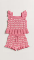 Pink knit outfit with top and shorts on a light gray background