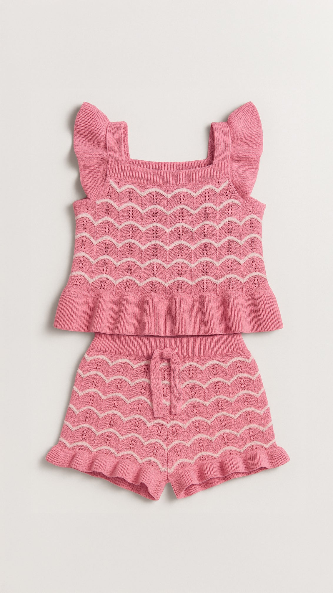 Pink knit outfit with top and shorts on a light gray background