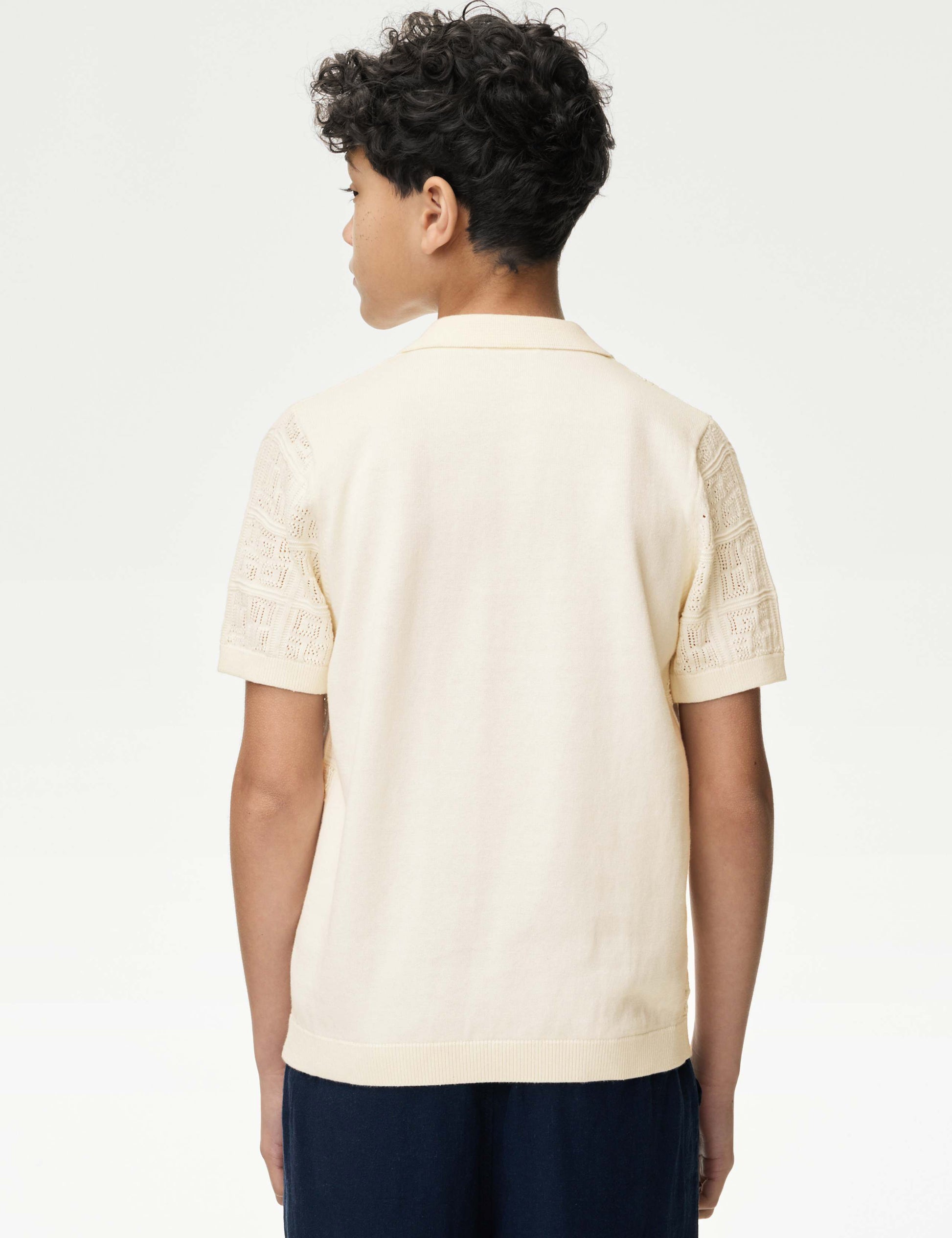 Child wearing a beige short-sleeve shirt with lace details on a white background