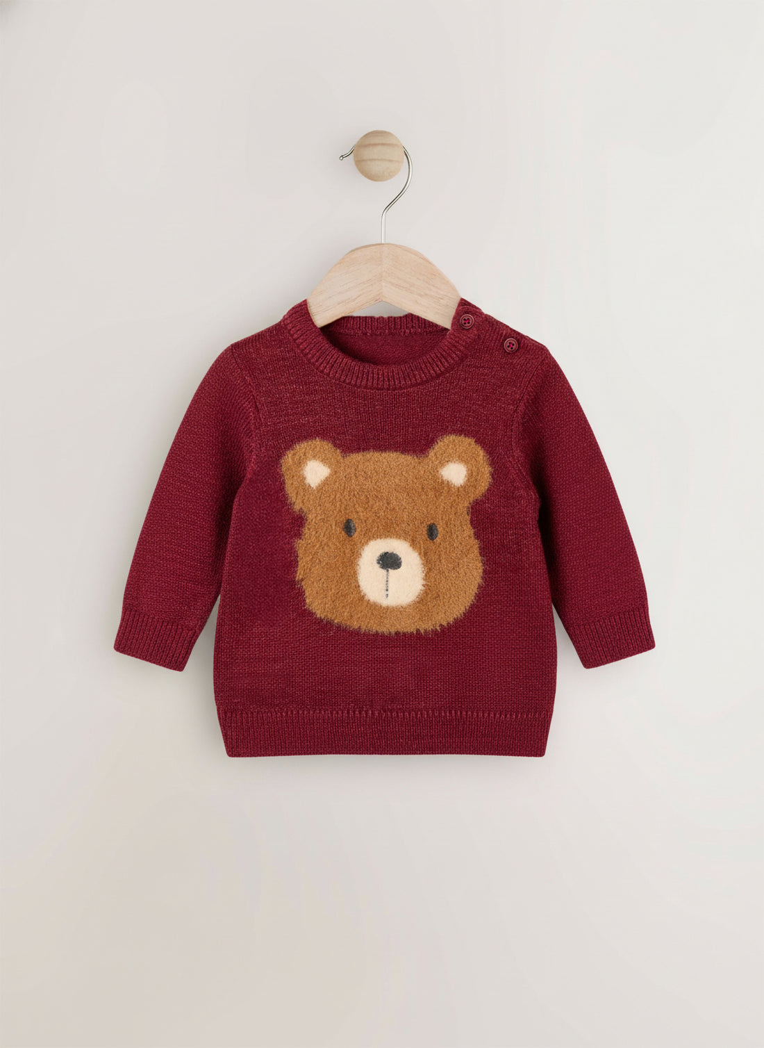 Red sweater with a bear face design on a wooden hanger against a white background