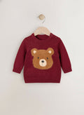 Red sweater with a bear face design on a wooden hanger against a white background