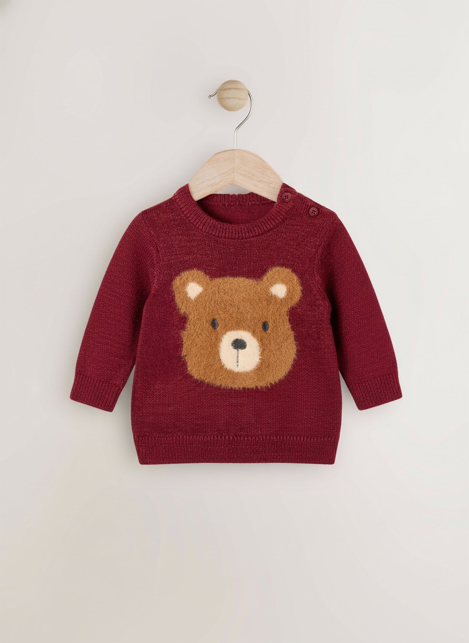 Red sweater with a bear face design on a wooden hanger against a white background