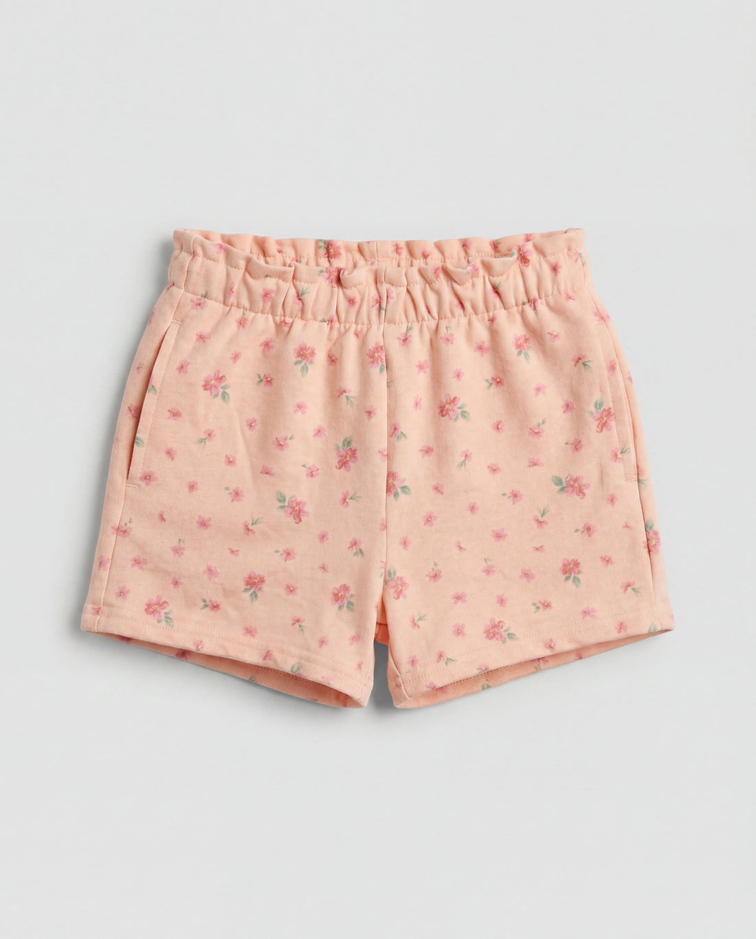 Front flat-lay view of girl's peach short pant with scattered pink ditsy floral print and elasticated paperbag waistband
