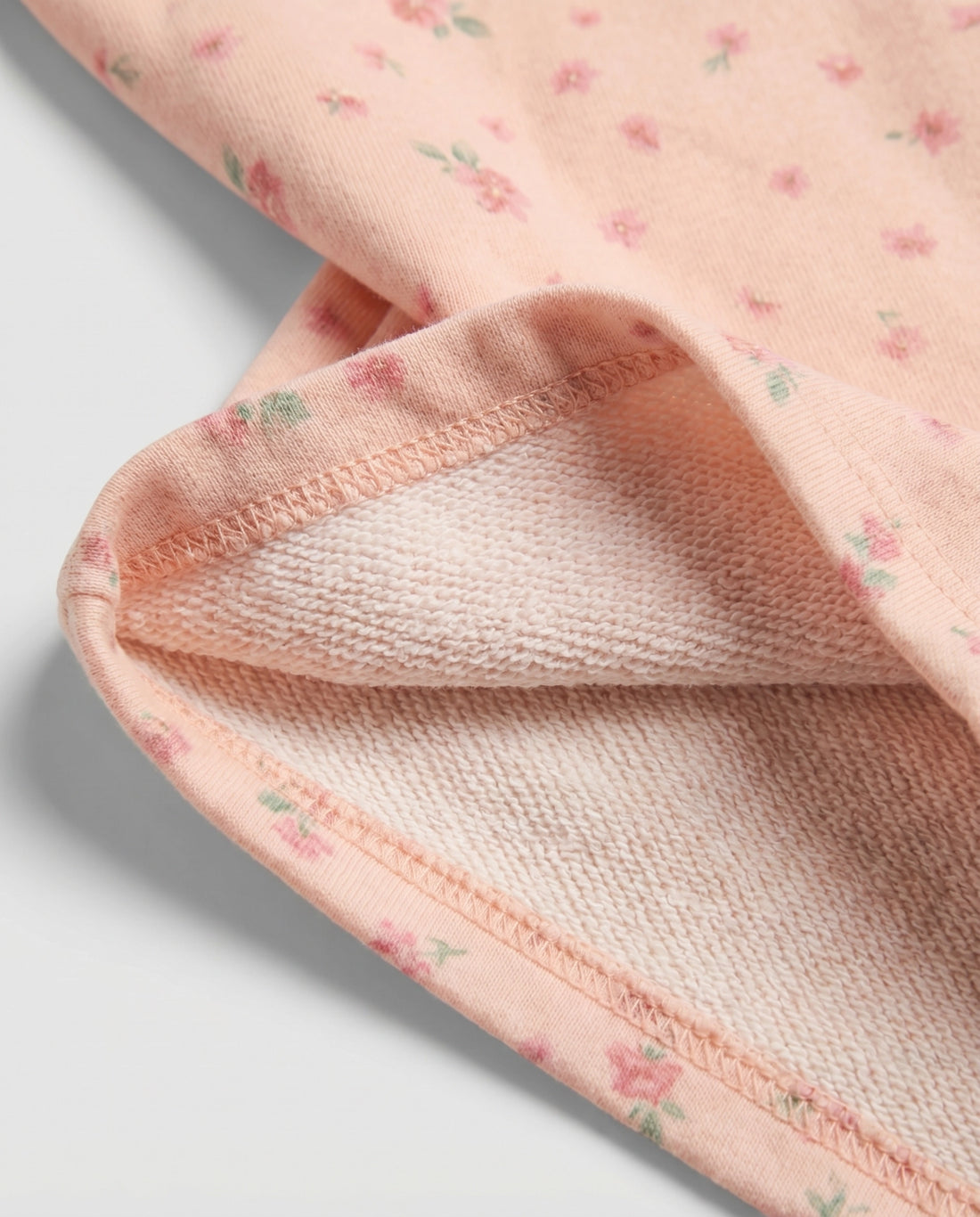 Front flat-lay view of girl's peach short pant with scattered pink ditsy floral print and elasticated paperbag waistband