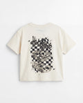 Back flat lay: Back view flat lay of an off-white toddler drop shoulder tee with a large black Hot Wheels race car graphic print on a checkerboard splatter background and Hot Wheels logo at the neckline.