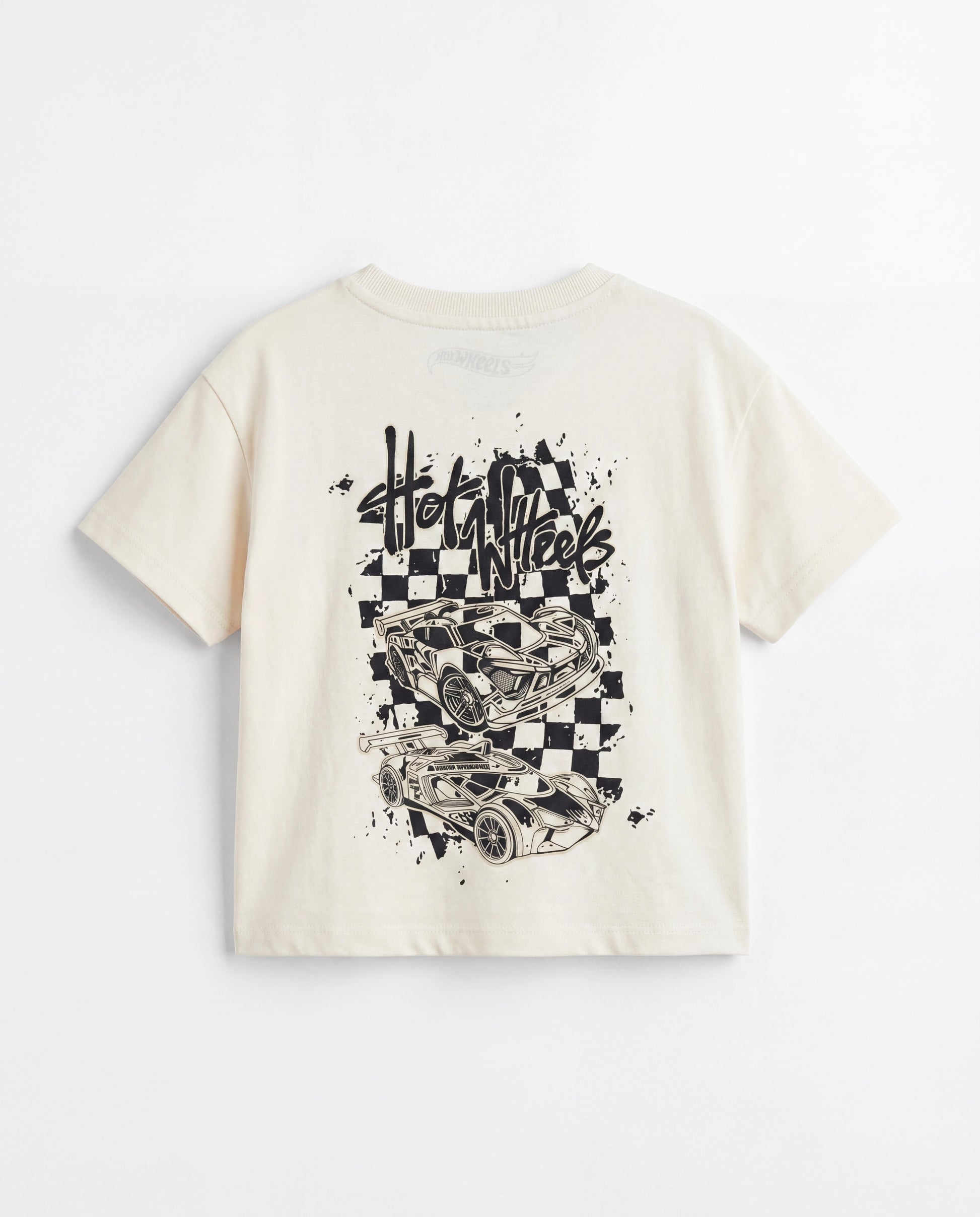 Back flat lay: Back view flat lay of an off-white toddler drop shoulder tee with a large black Hot Wheels race car graphic print on a checkerboard splatter background and Hot Wheels logo at the neckline.