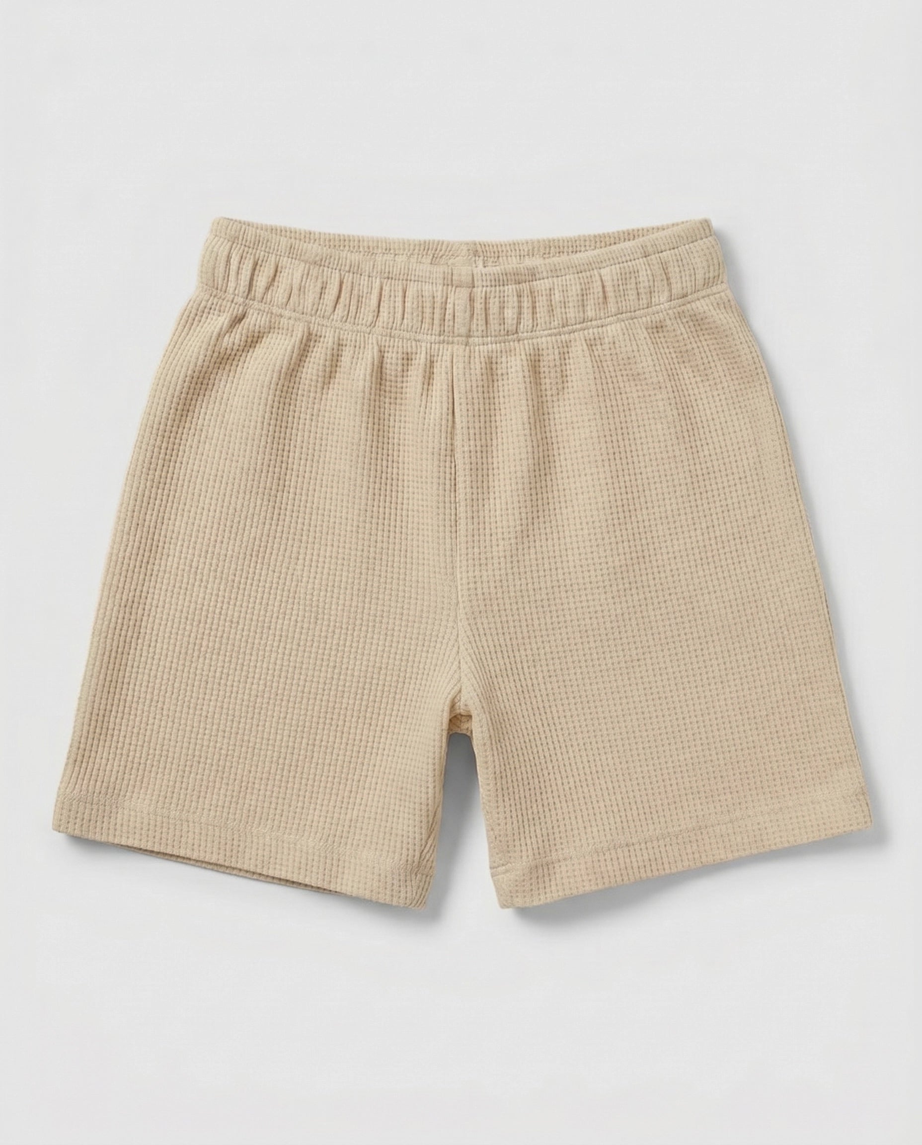 Full front flat-lay view of toddler waffle cotton short pants in warm beige with elasticated waistband and relaxed short-length silhouette on a light grey background.