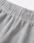 Close-up of toddler waffle-knit cotton short pants in light grey showing elasticated waistband detail and distinctive grid-textured fabric surface.