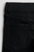 Close-up of black pants with a pocket on a light gray background
