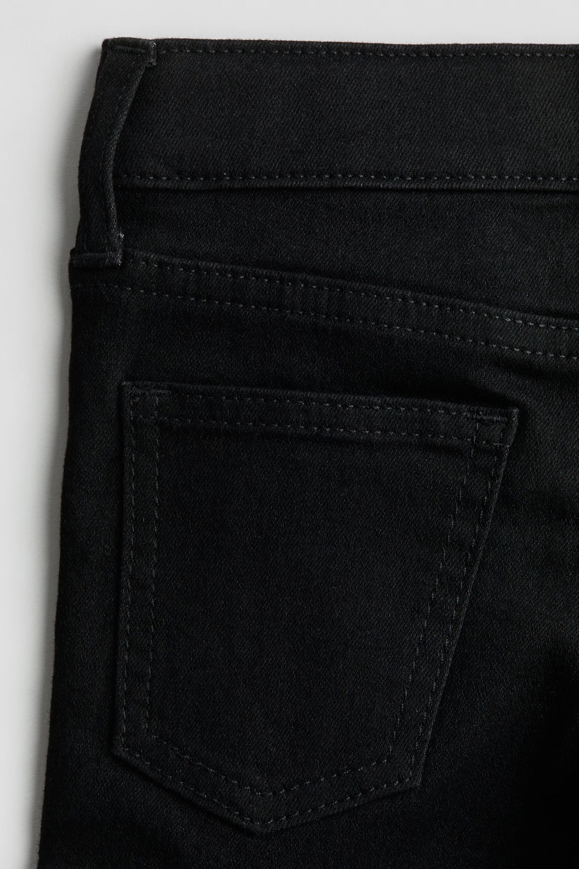 Close-up of black pants with a pocket on a light gray background