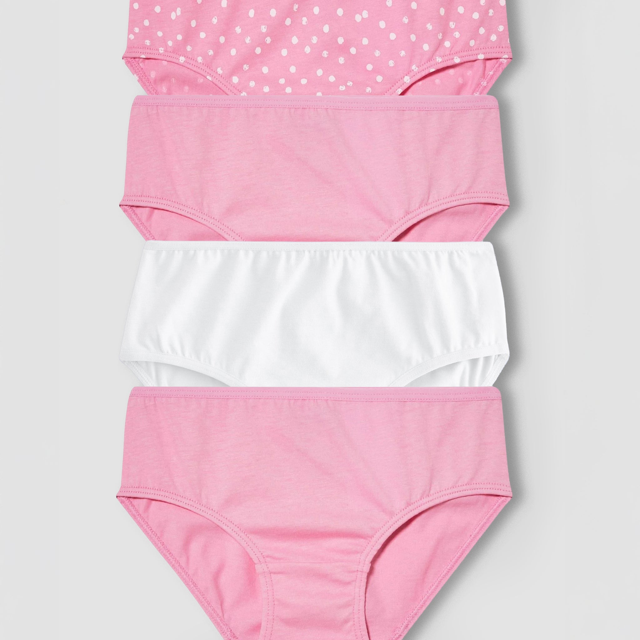 Set of four pairs of girl's underwear with different patterns on a light gray background