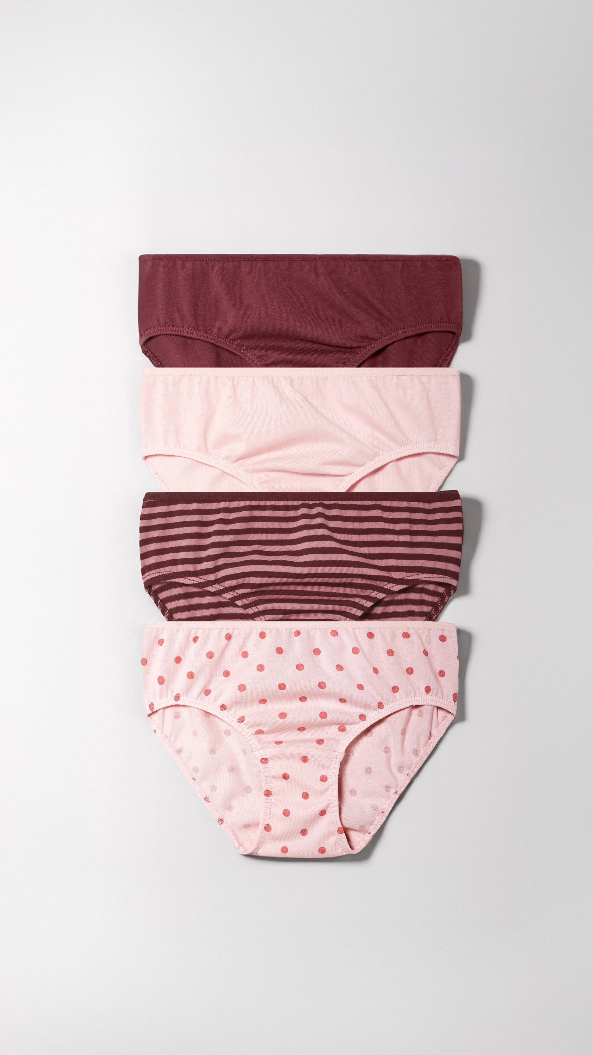 Set of four girl's underwear with different patterns on a light gray background