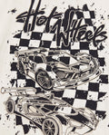 Close-up of the back graphic on an off-white toddler tee showing a black screen print of two Hot Wheels race cars over a splatter checkerboard background with graffiti-style 