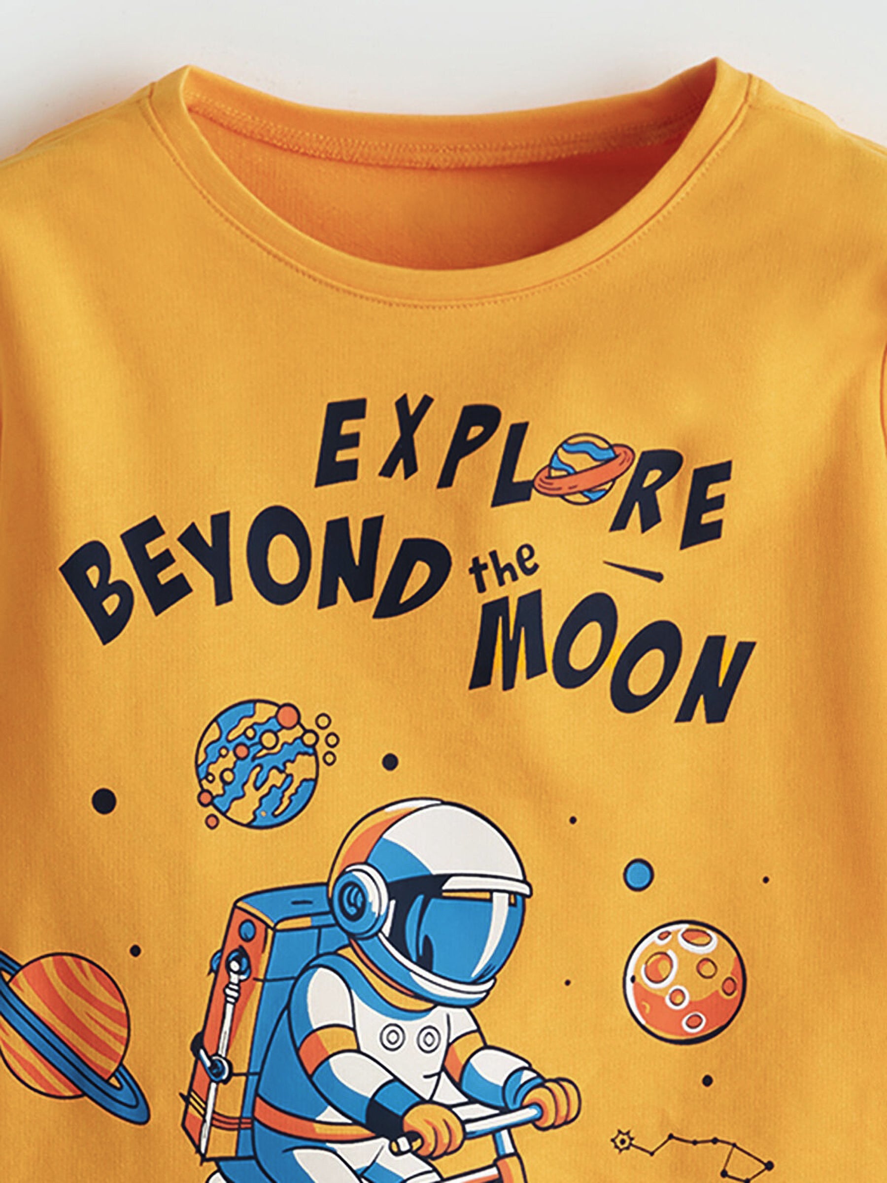 Yellow t-shirt with an astronaut graphic and text 'Explore Beyond the Moon' on a white background