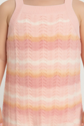 Young girl standing wearing a striped Jumpsuit against a beige background