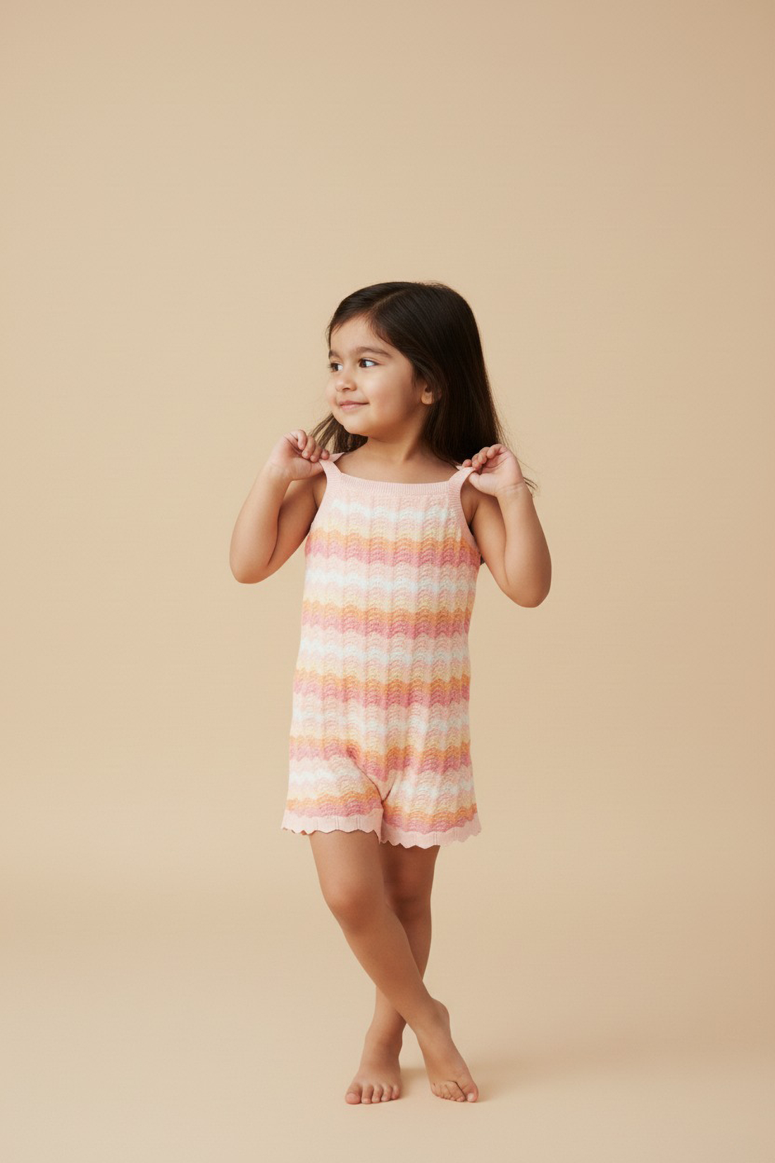Young girl wearing a striped Jumpsuit against a beige background