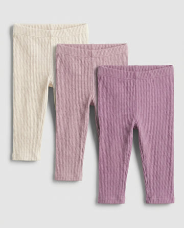 Baby girls' cable-knit leggings 3-pack in cream, blush pink, and mauve purple, flat lay on grey background