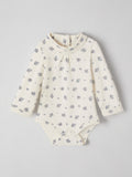 White baby onesie with floral pattern on a light gray background