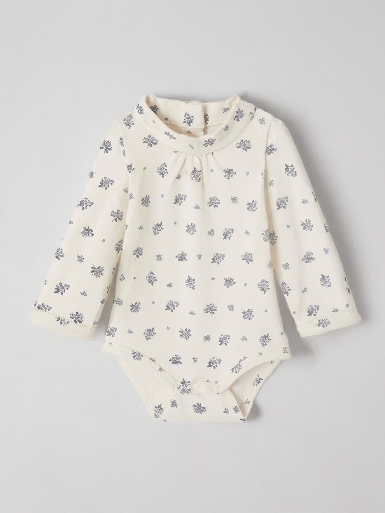 White baby onesie with floral pattern on a light gray background