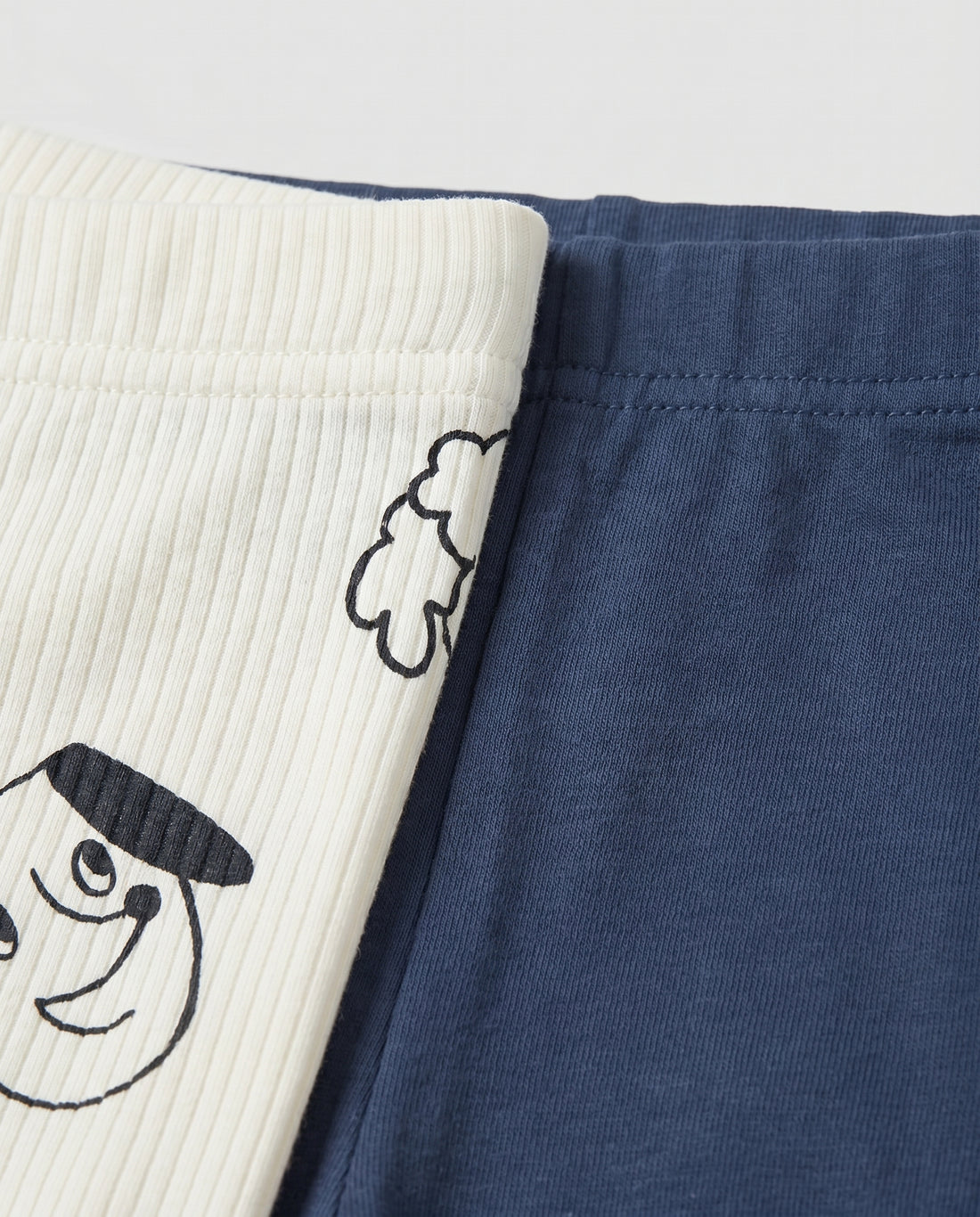 PTex Fashion navy blue baby knit jogger pants with cute hand-drawn animal face prints on the knees and ribbed cuffed ankles, laid flat on a light grey background