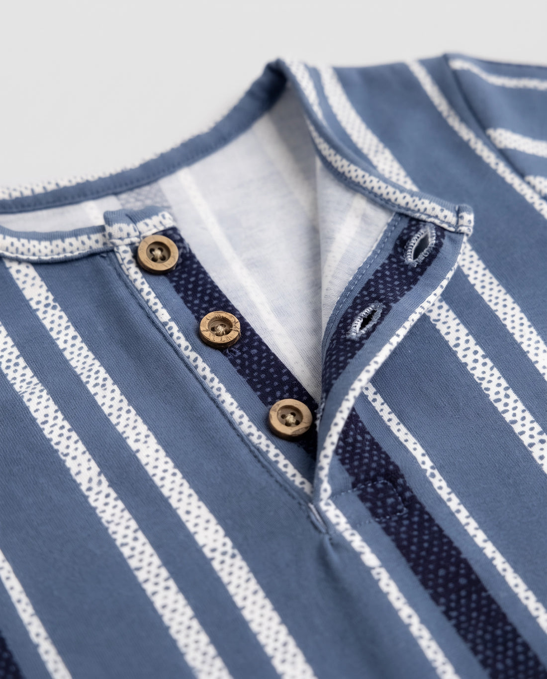 Blue striped baby romper on a wooden hanger showing button placket and leg press studs — PTex Fashion
