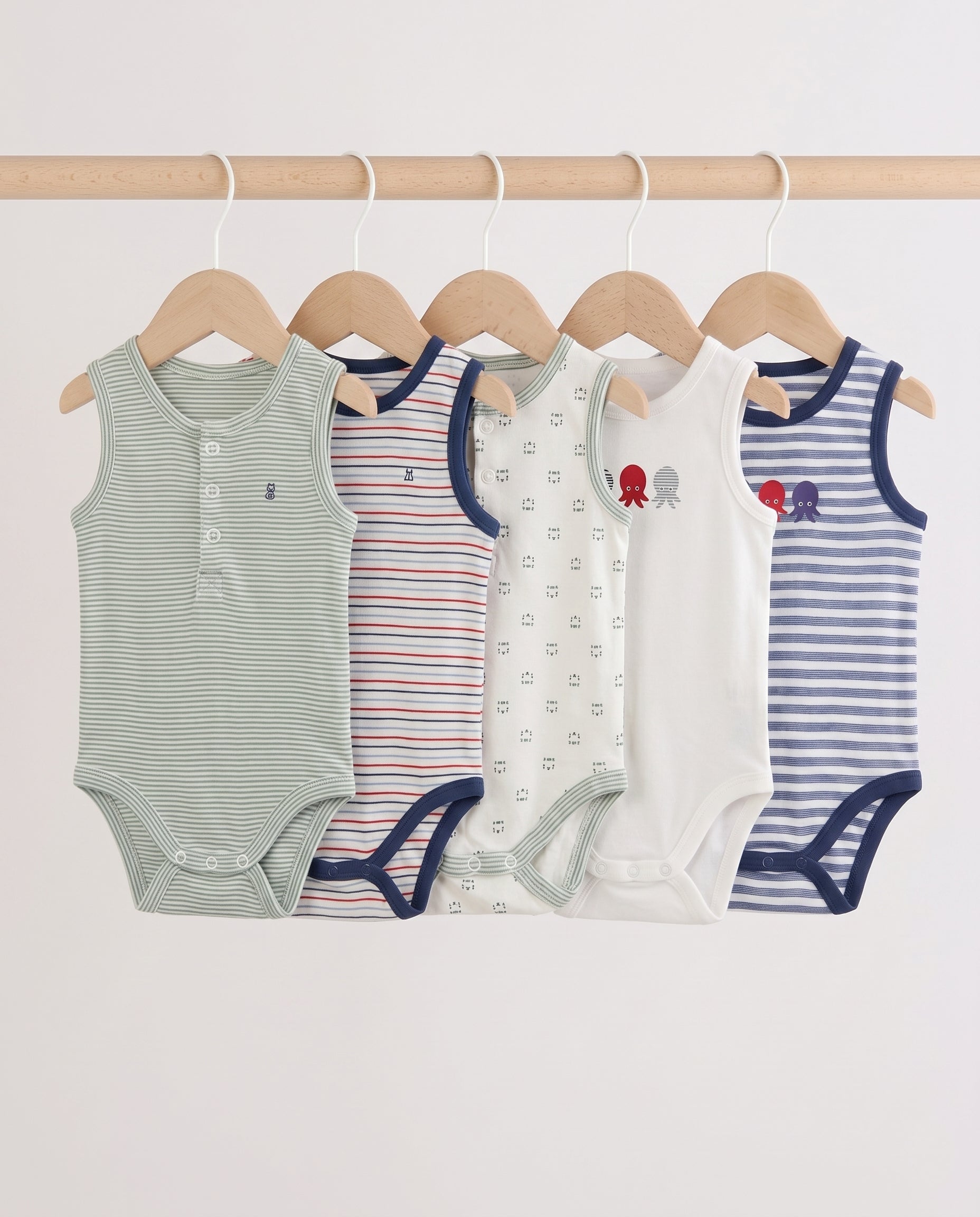 Five baby sleeveless bodysuits in mixed stripe and print designs hanging on wooden hangers — sage stripe, red multi-stripe, cream print, white octopus graphic, and blue stripe