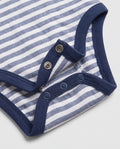 Close-up of baby bodysuit crotch snap fasteners on blue and white striped cotton fabric with navy ribbed trim