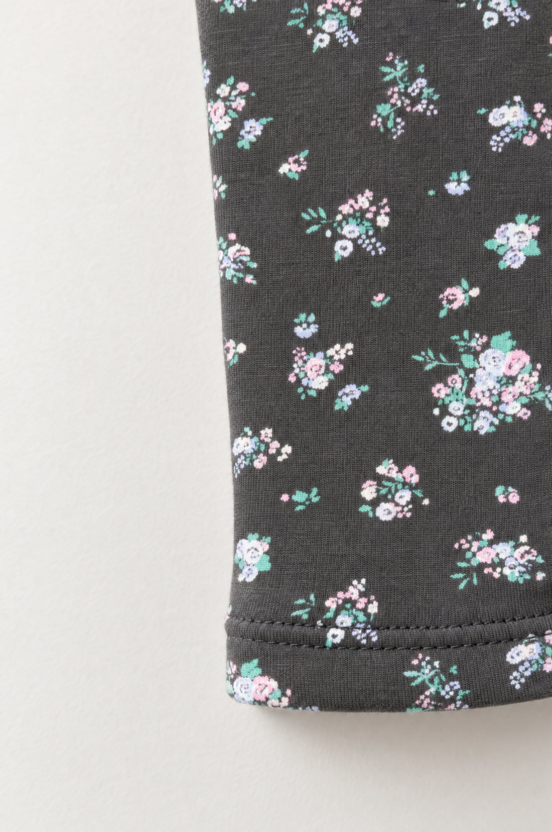 Baby girl charcoal leggings with pink, lilac, white and green floral print, elasticated waistband and neatly stitched leg hems.