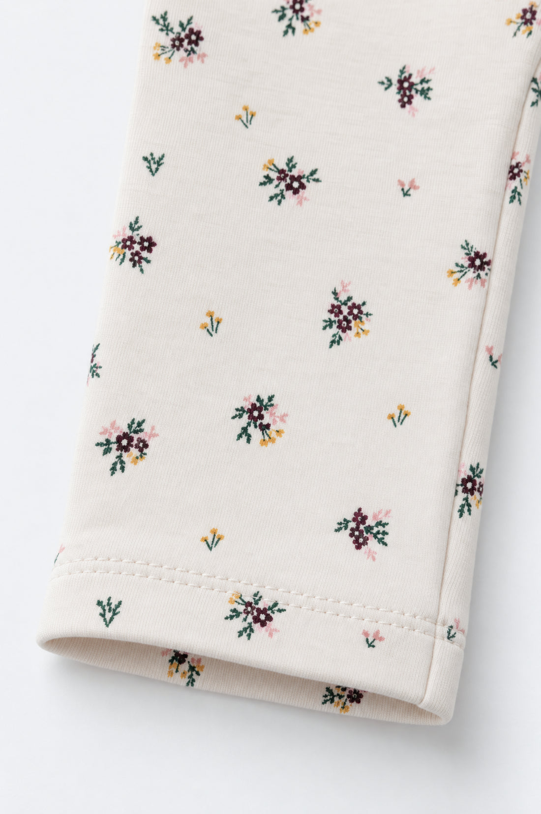 Baby girl cream leggings with tiny burgundy, pink, mustard and green floral print, elasticated waistband and neatly stitched hems.
