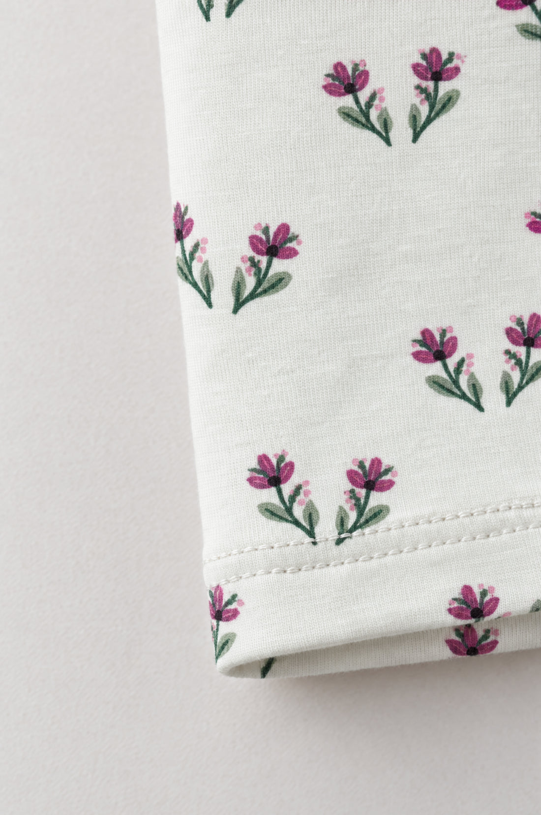 Baby girl off-white leggings with small pink and green floral print, elasticated waistband and neatly finished hems.