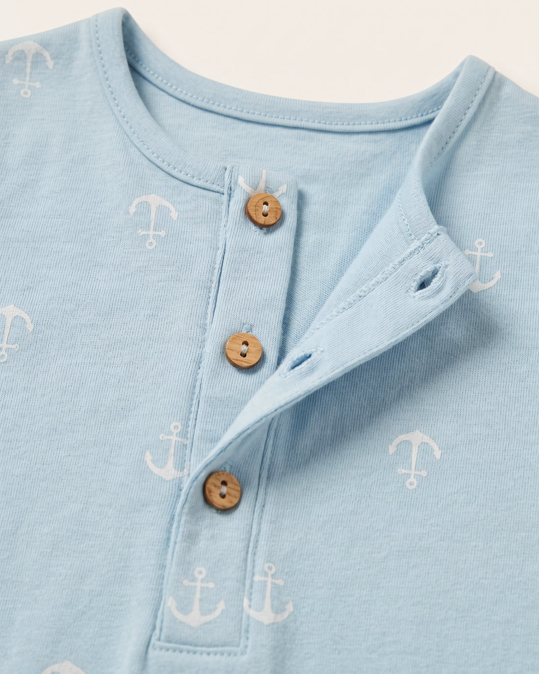 Full front view of baby boys' sleeveless blue anchor print romper with patch pockets and boat badge detail